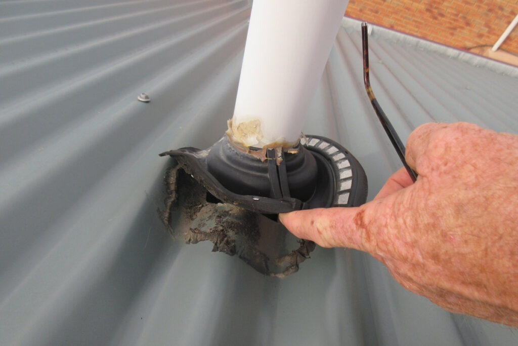 Hobart building inspector checking leaking roof pipe penetration and flashing damage